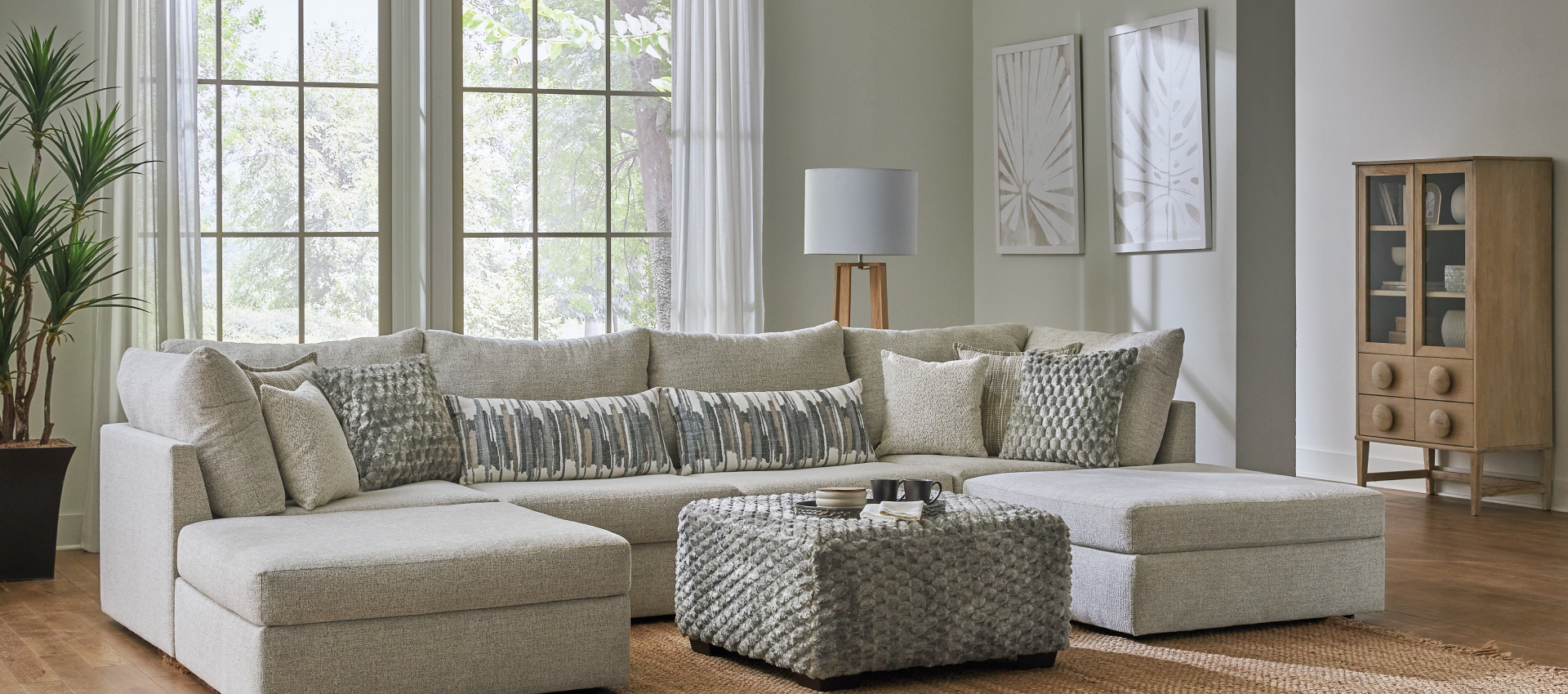 A living room with white furniture and a large window.